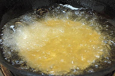Oil sizzles to cook the raw dough